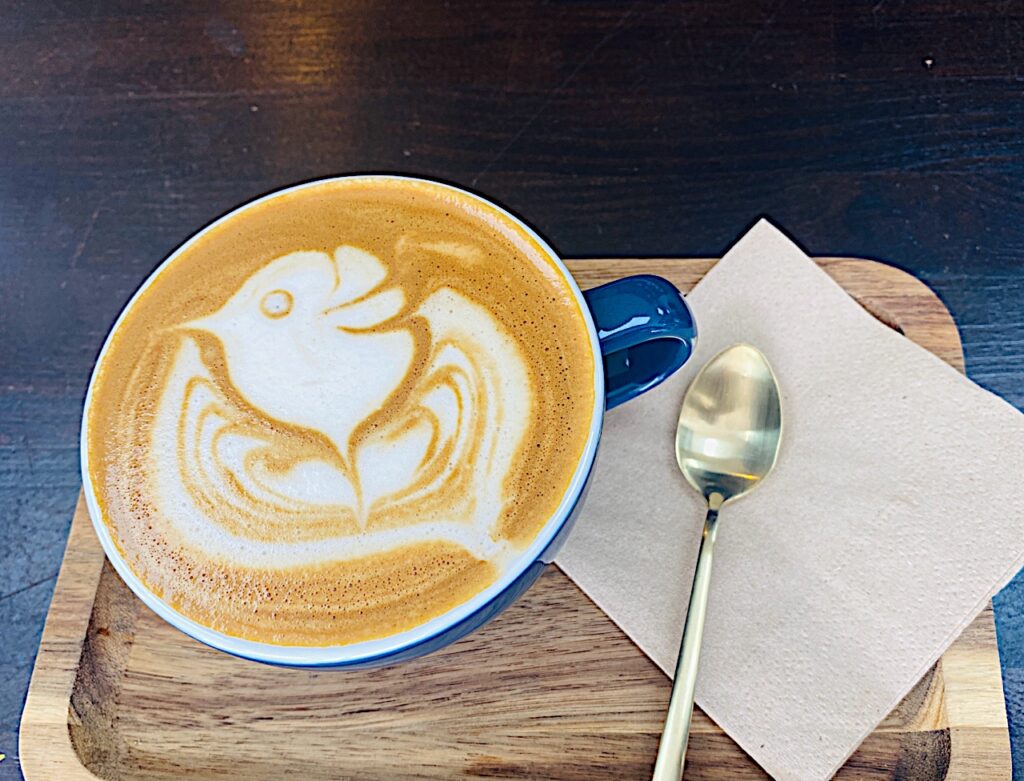Cafe de especialidad con excelente pinta. Tiene un dibujo de un pez y taza azul