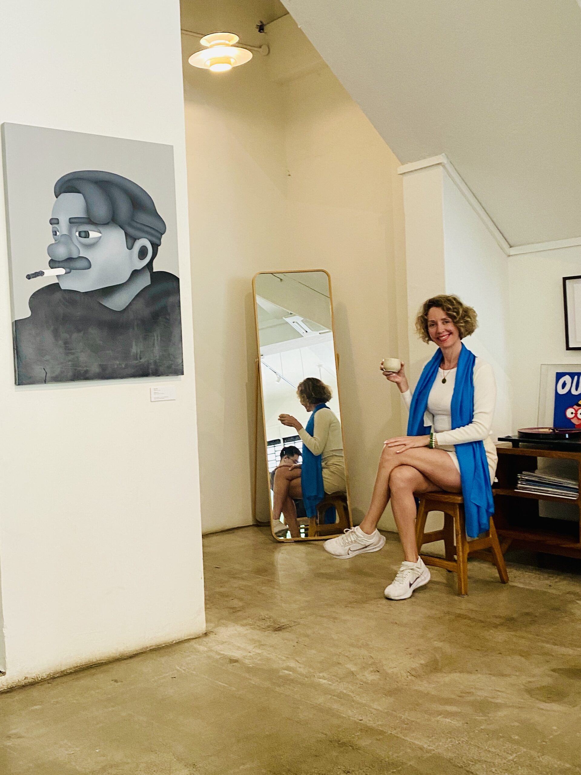 Dr Carolina Díez saboreando un cafe de especialidad con un espejo de fondo donde se refleja la imagen y una pintura de un señor disfrutando de un puro